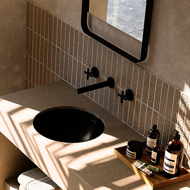 beiges Badezimmer mit schwarzen Akzenten wie Waschbecken, Armaturen, Spiegel